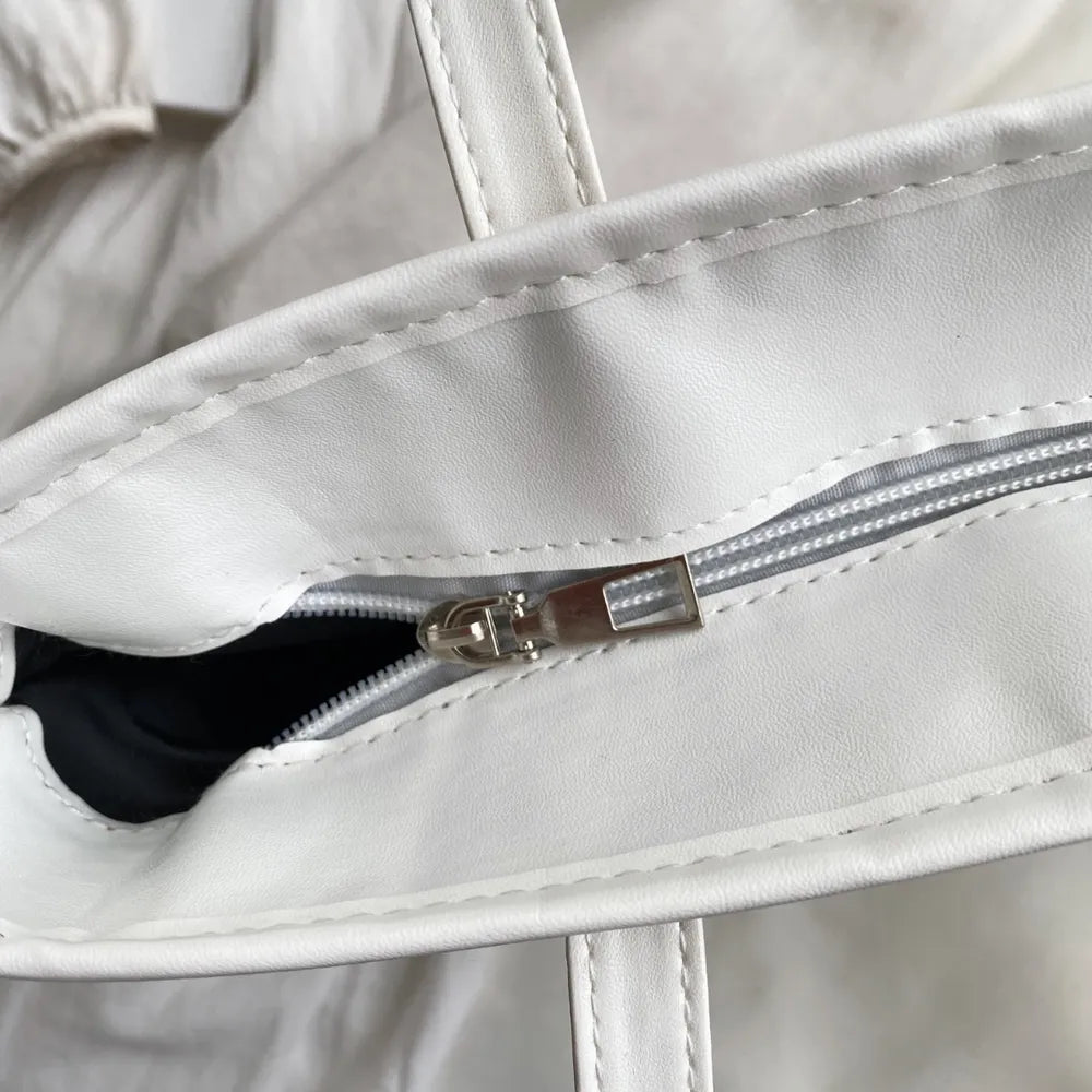 Large white straw bag laying down on white cloth.