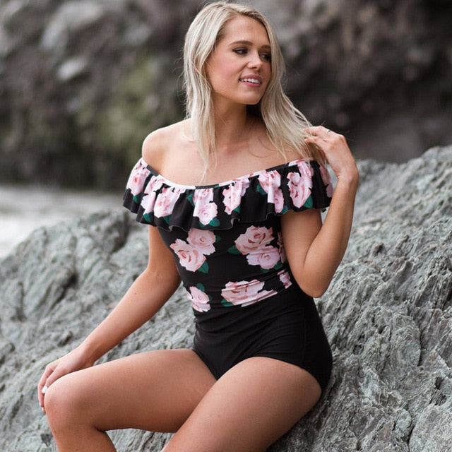Woman wearing a floral top and black shorts standing against a rocky background sold at PeachyBeanz.