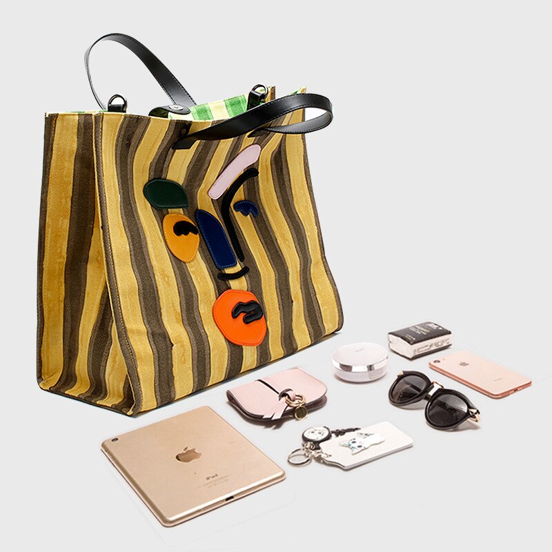 Large yellow striped canvas tote with polyester cotton lining. Modern faceless print, reinforced handles, perfect for beach days and everyday errands.