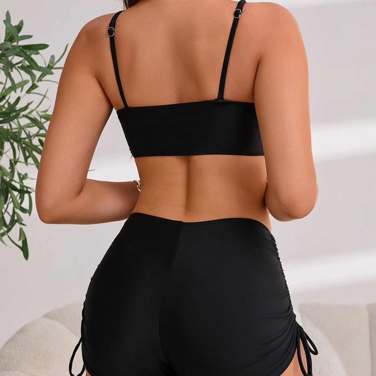 Person wearing a black bikini with a neutral background