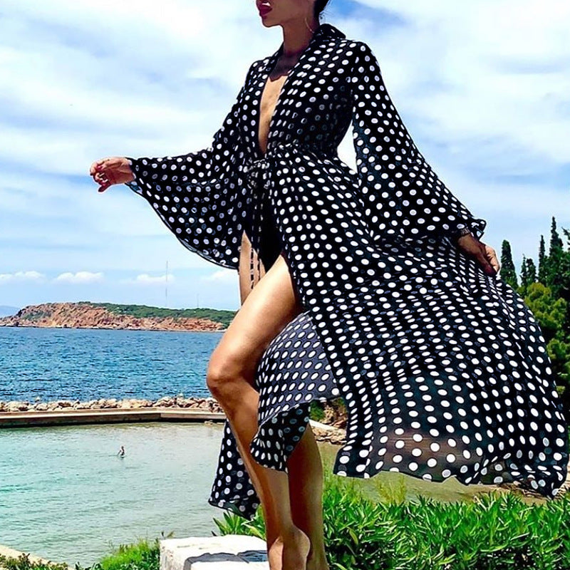 Person wearing a black and white polka dot dress by a scenic coastal area.
