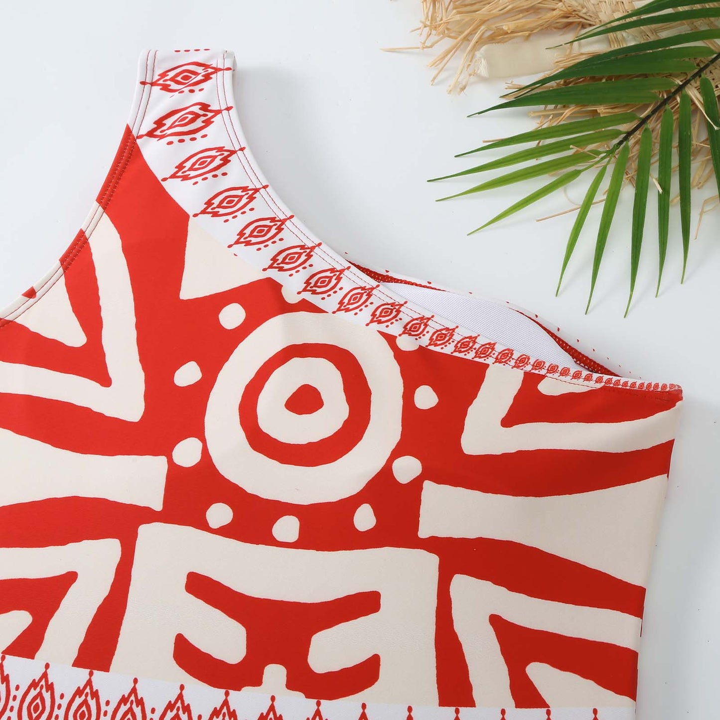Red and white patterned top on a white background with palm leaves