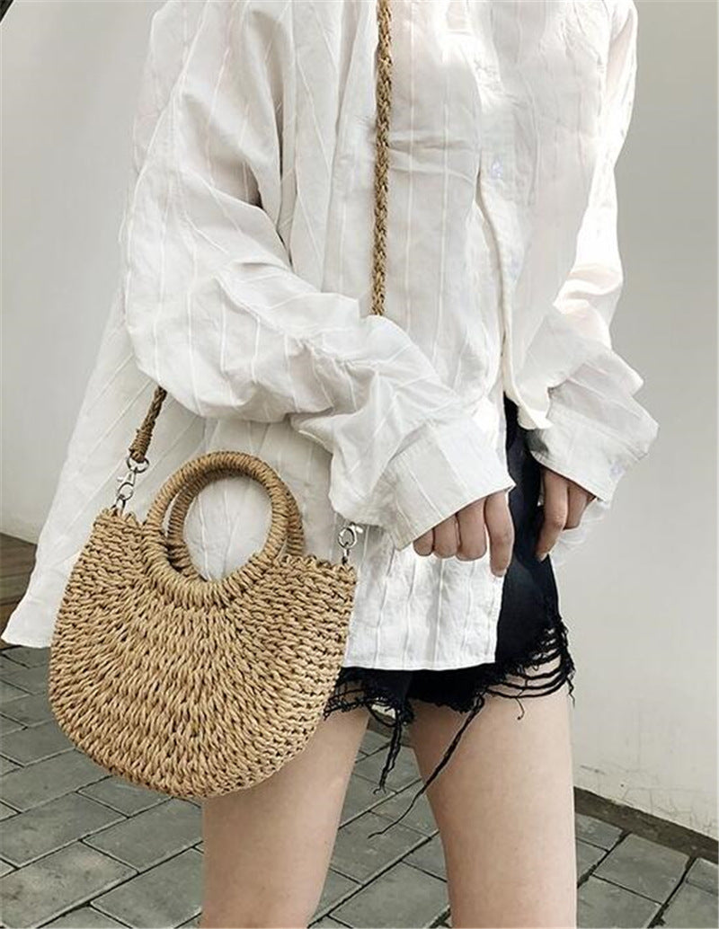Person holding a woven handbag wearing a white shirt and black shorts.