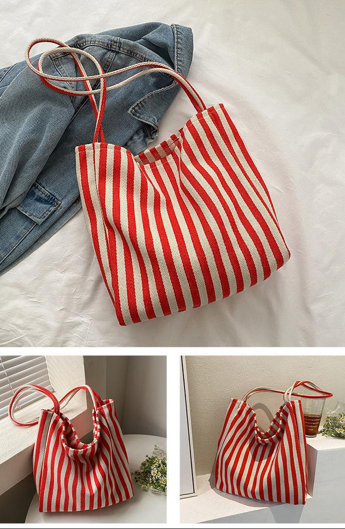 Red and white striped bag with denim jacket on a light gray background