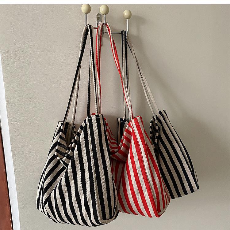 Striped bags hanging on a hook against a plain wall