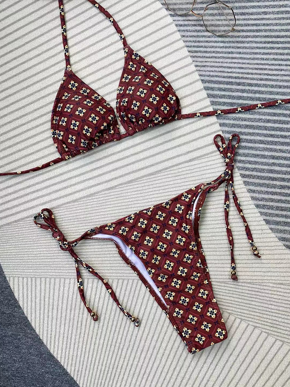 Maroon patterned bikini set on a striped fabric background