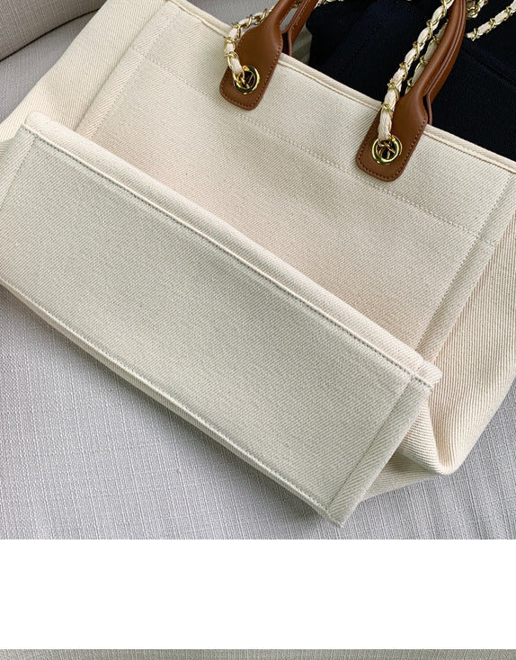 Beige handbag with brown handles on a light gray surface. Sold at PeachyBeanz.