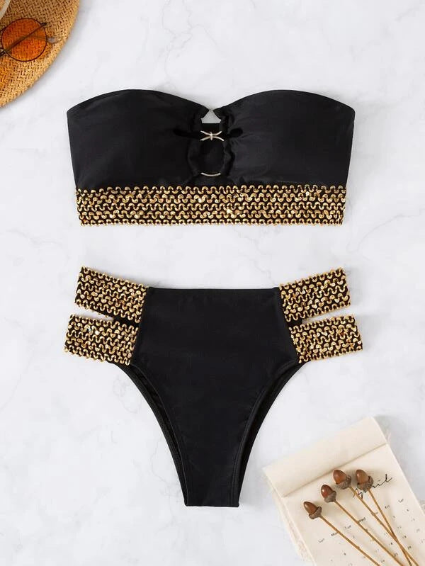 Black bikini set with gold accents on a white surface