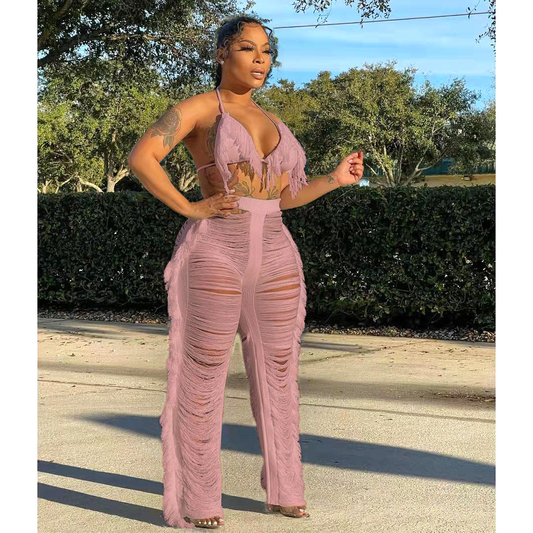 Woman wearing a pink mesh jumpsuit standing outdoors with trees in the background
