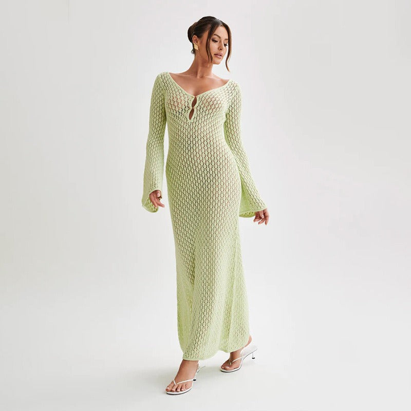 Woman in a green textured dress standing in front of a building entrance.