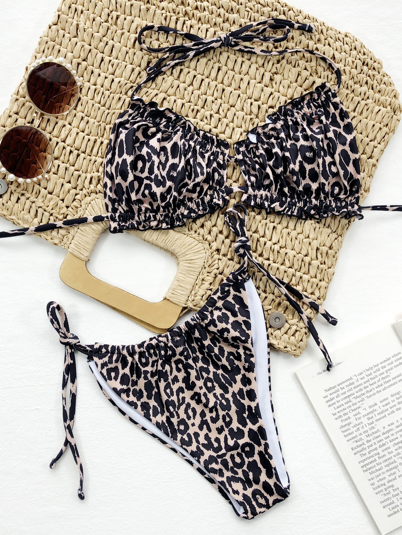 Leopard print bikini set with a straw bag and sunglasses on a white background