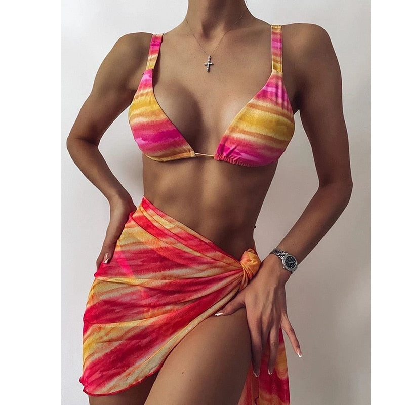 Woman in rainbow printed bikini set against a plain background.