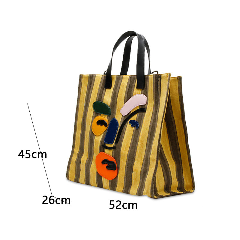 Striped tote bag with artistic face design and measurements on a white background