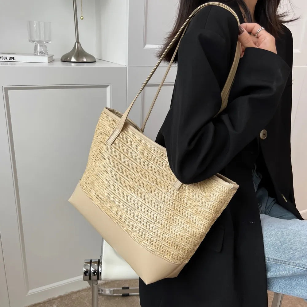 Woman holding a large beige straw bag.