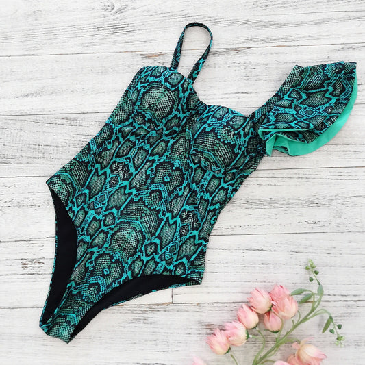 Teal and black patterned swimsuit on a wooden surface