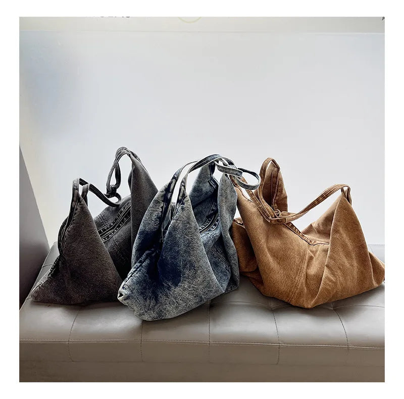 Three handbags in different colors on a light-colored couch.