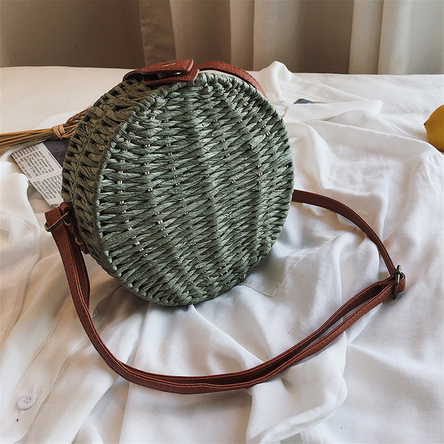 Woven handbag with leather straps on a white background