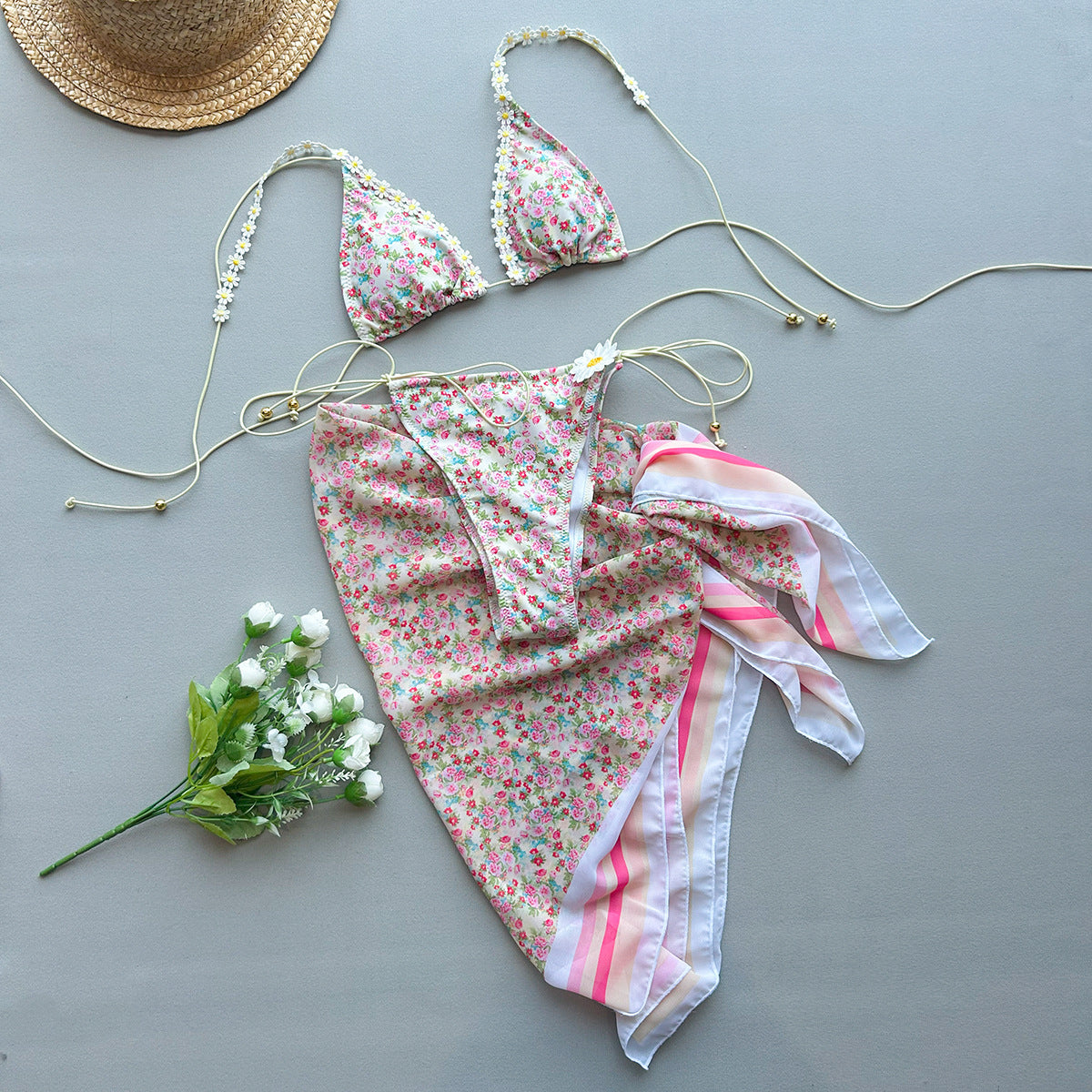Three-piece bikini laying on a plain background