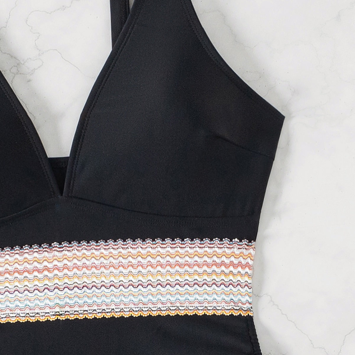 Black swimsuit with tie ups on the sides standing against a white background