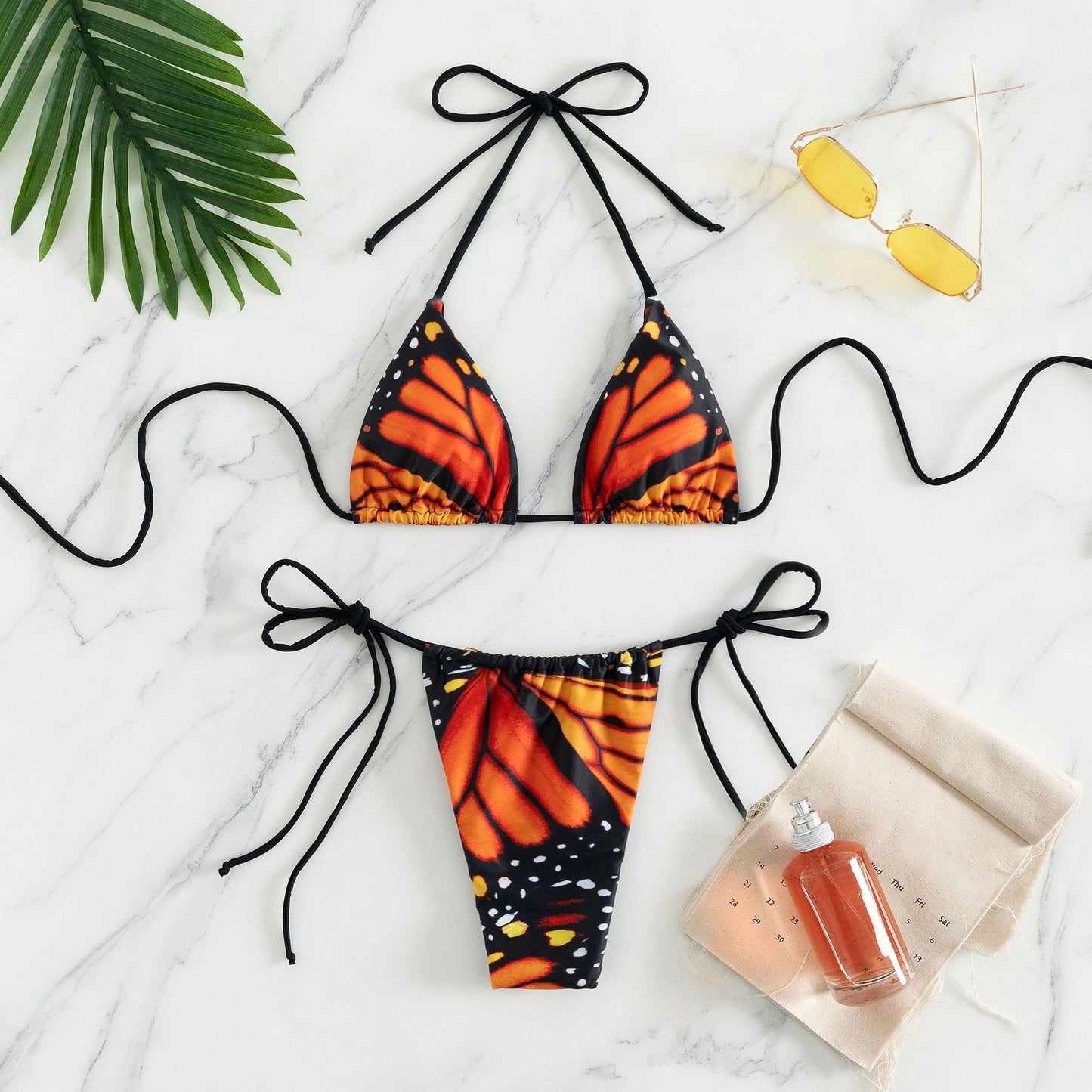 Black bikini top and butterfly-patterned bottom on a marble 