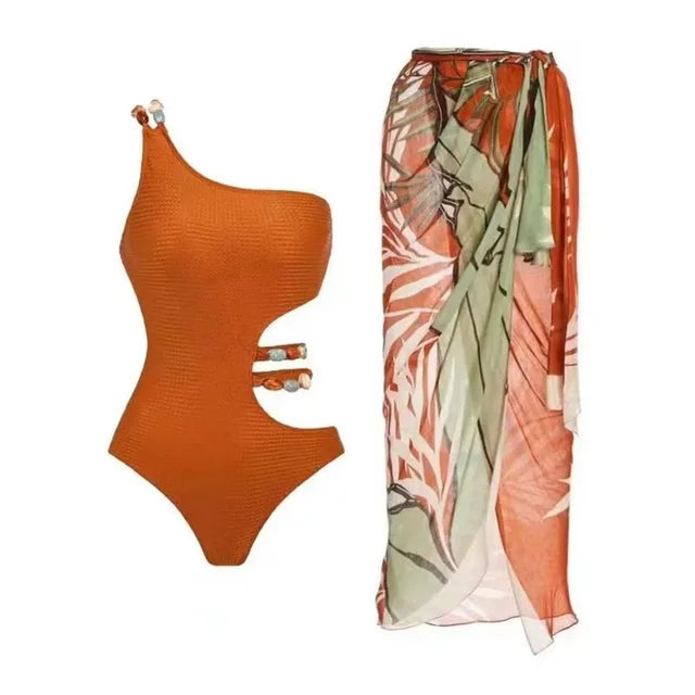 Orange swimsuit with skirt cover-up with leaf patterns against a white 