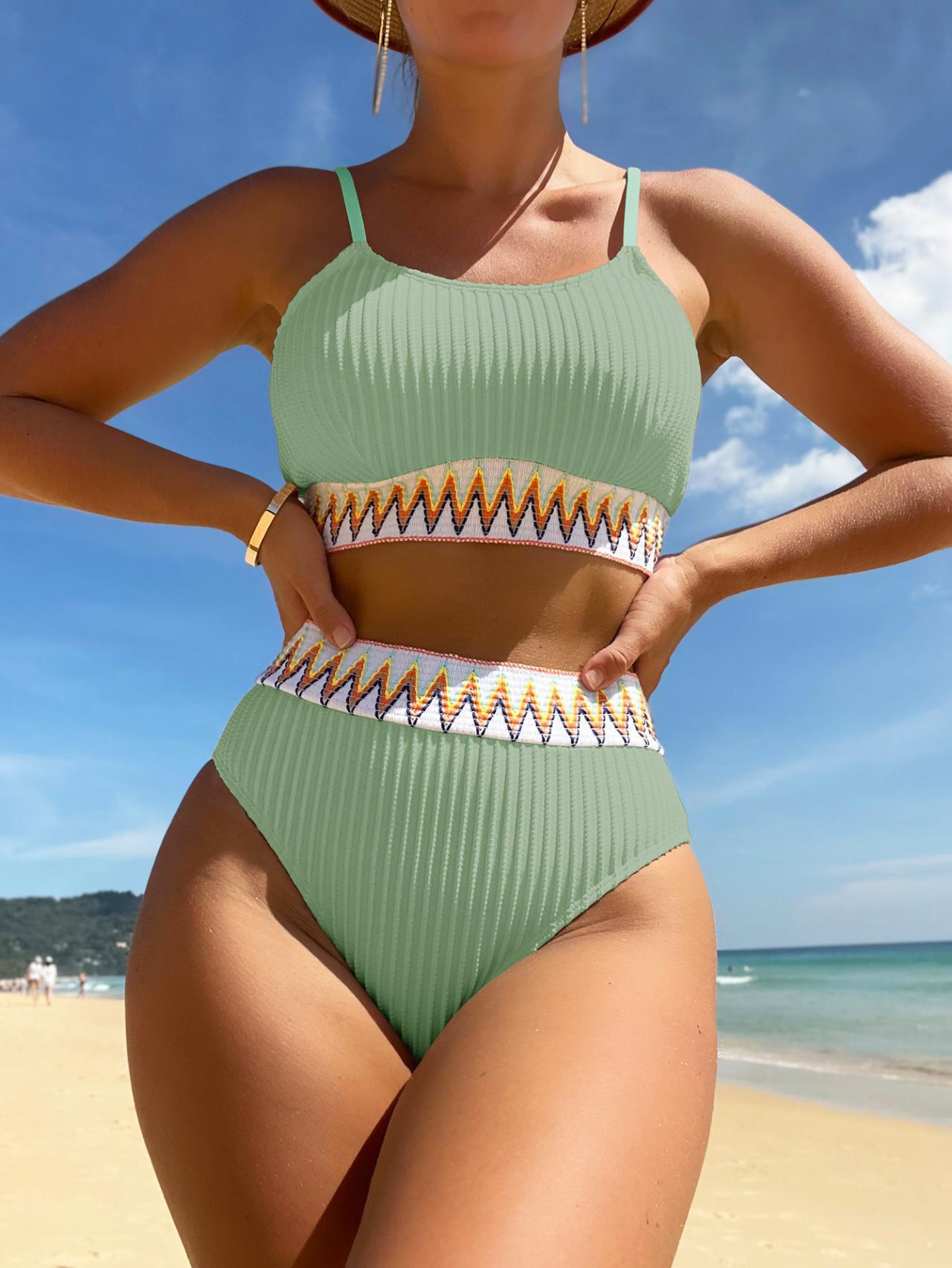 Person wearing a green bikini with gold accents on a beach