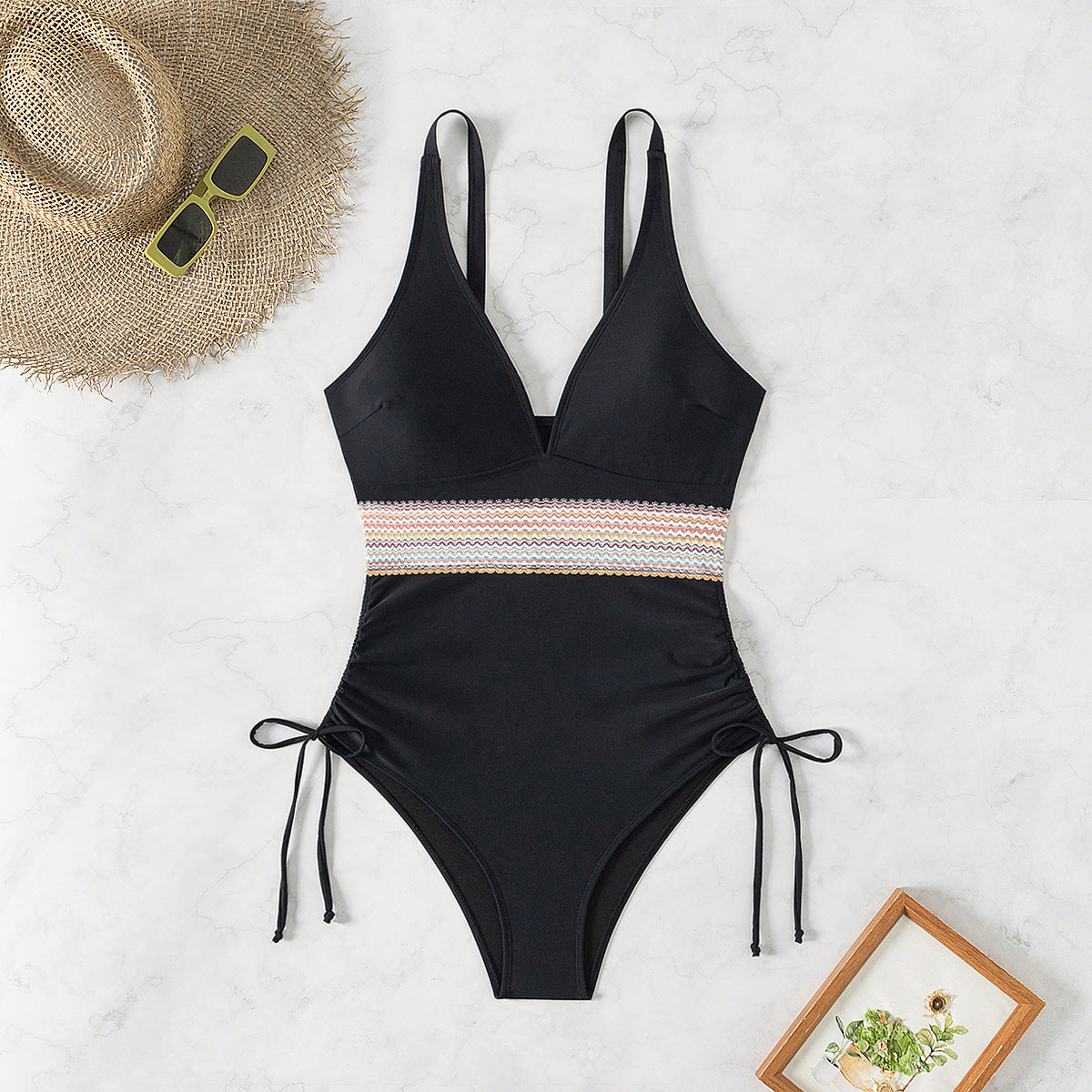 Black swimsuit with tie ups on the sides standing against a white background