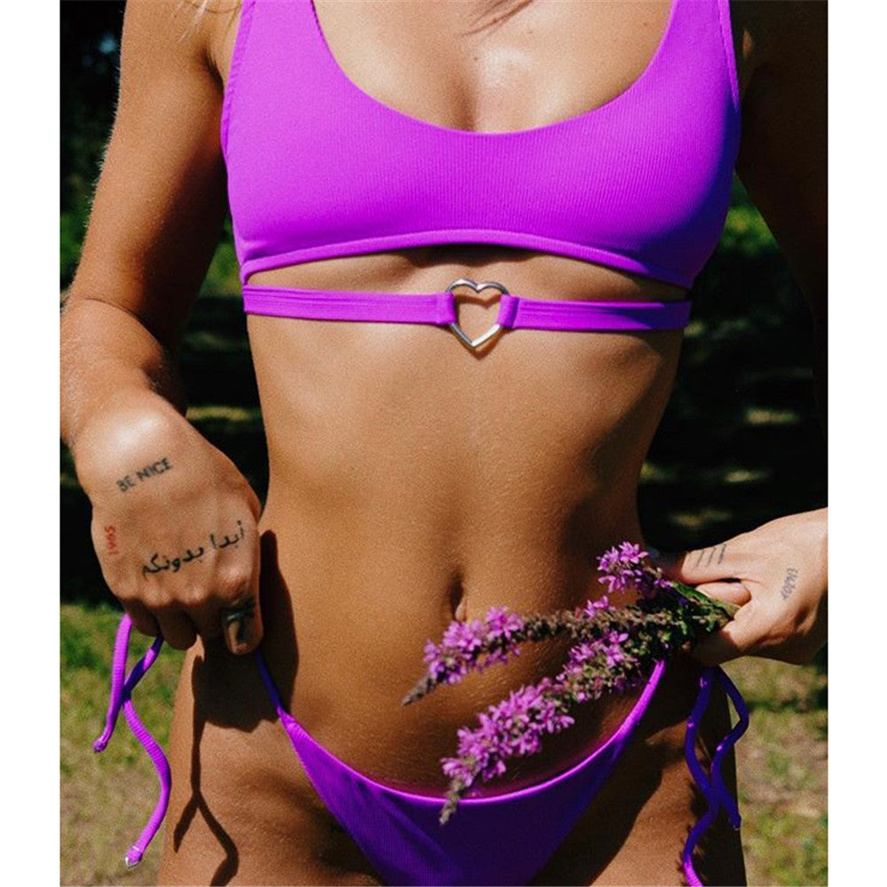 Person wearing a bright purple bikini with a heart-shaped clasp against a neutral background sold at PeachyBeanz.