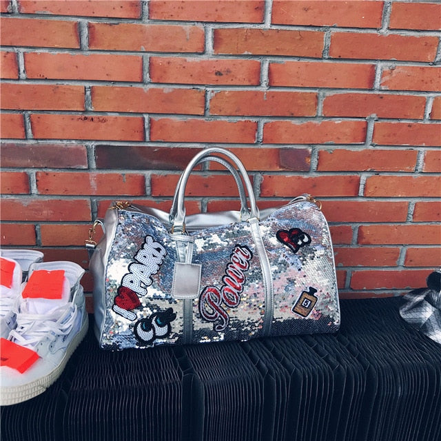 Silver sequin clutch with 'I ❤️ Parks' text against a brick wall.