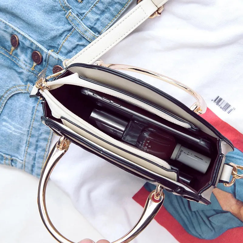 Open handbag with gold handles and interior showing a bottle of perfume and other items, on a denim background.