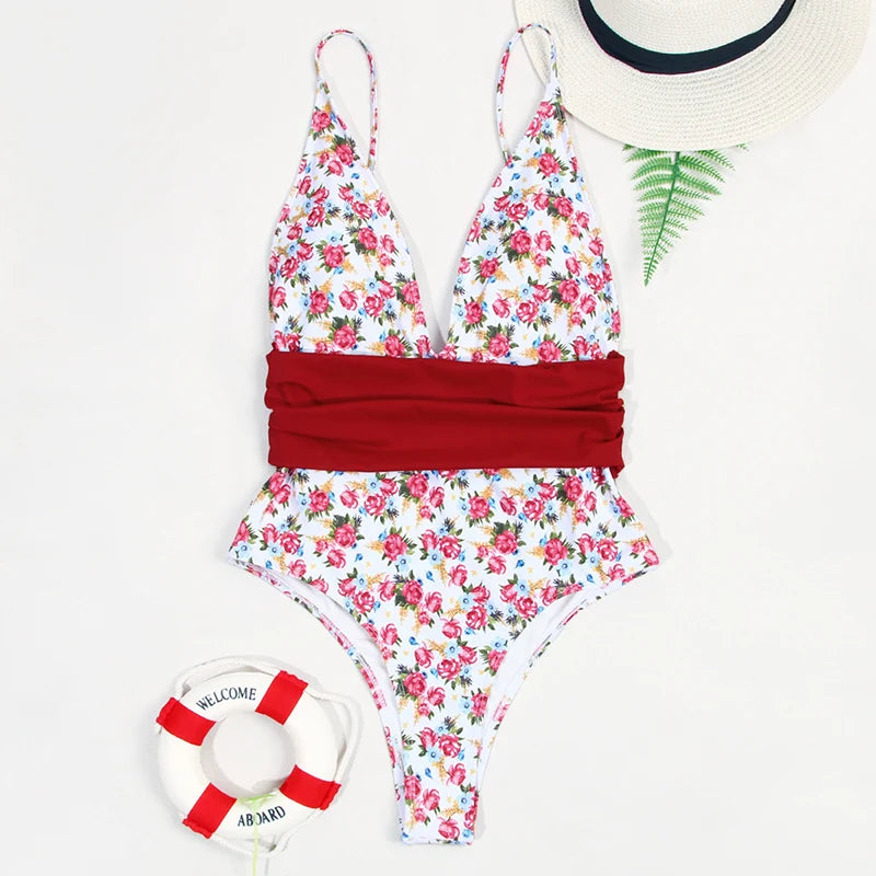 Floral swimsuit with red accents, sun hat, and life buoy on a white background
