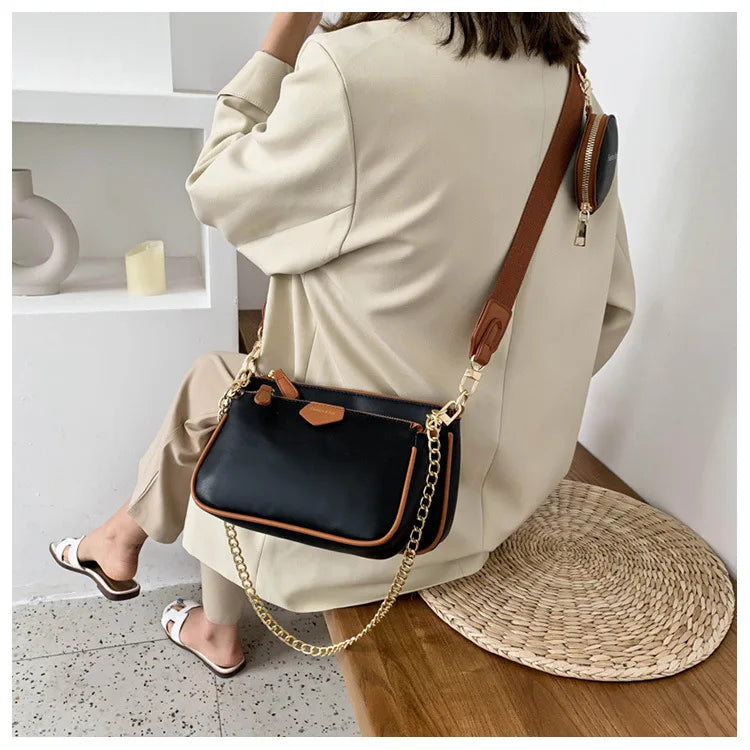 Person wearing a black handbag with a gold chain strap in an indoor setting