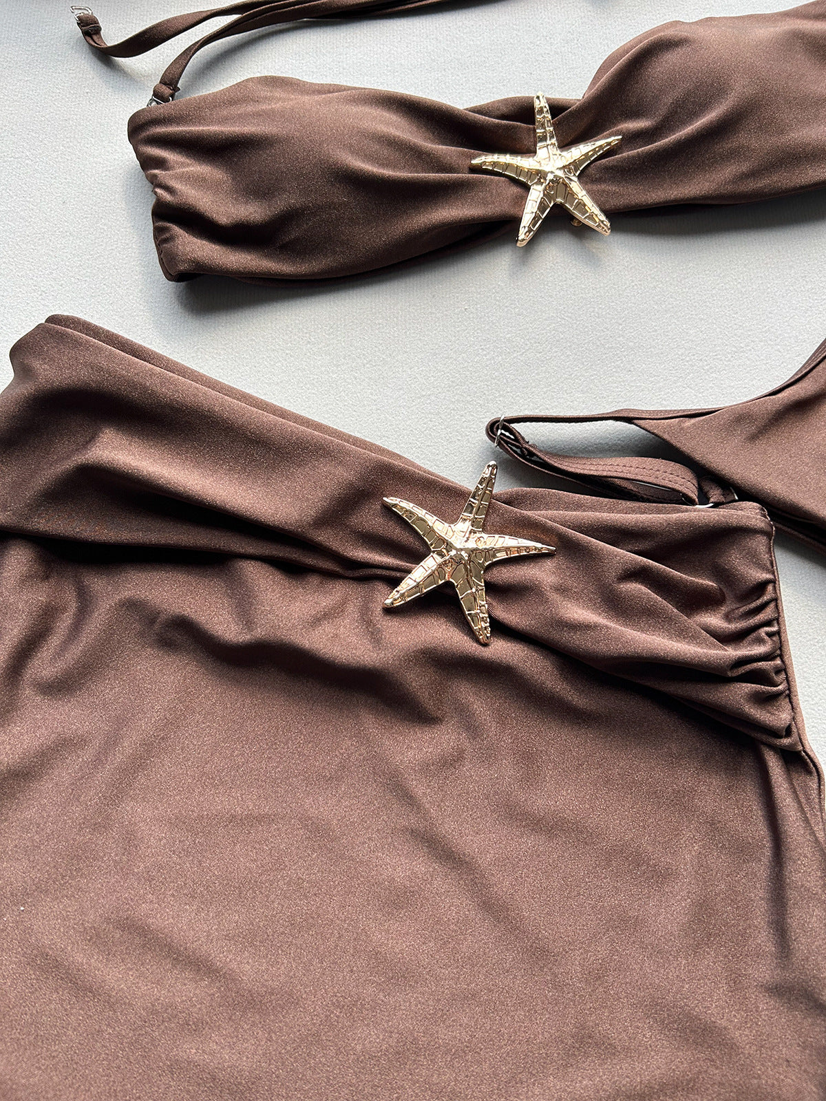 Brown bikini set with starfish decorations on a light gray background