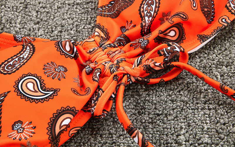 Orange fabric with black paisley pattern on a gray carpet