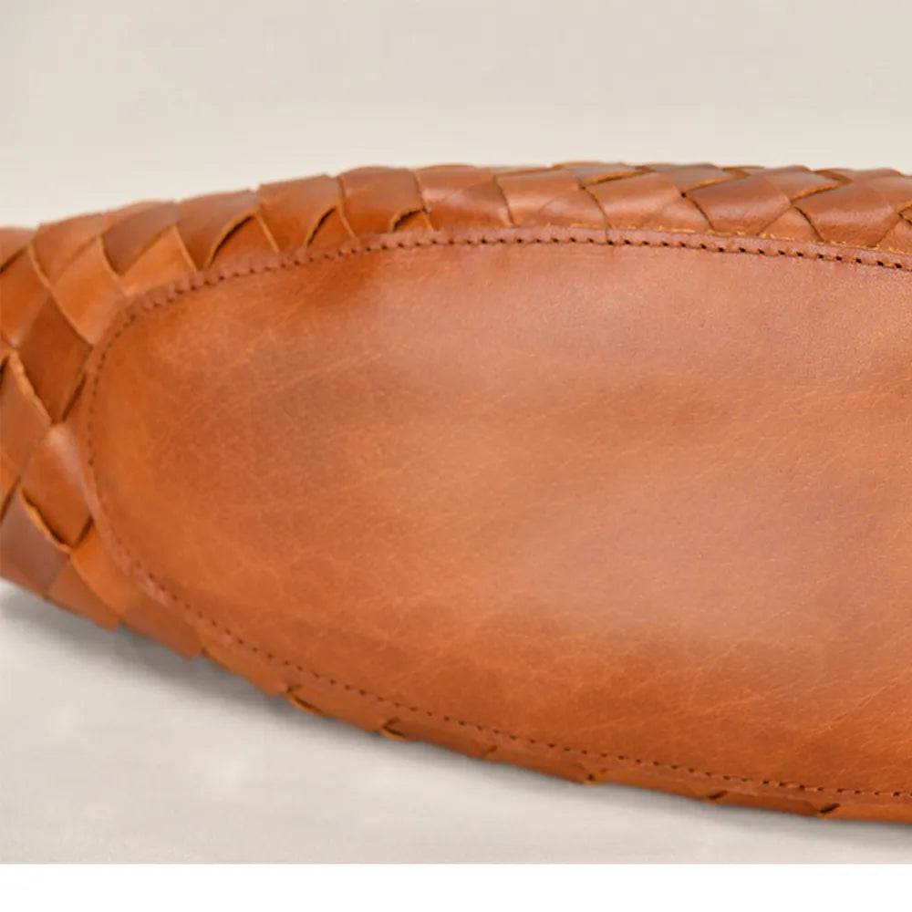 Close-up of a brown leather shoe with woven pattern on a beige background
