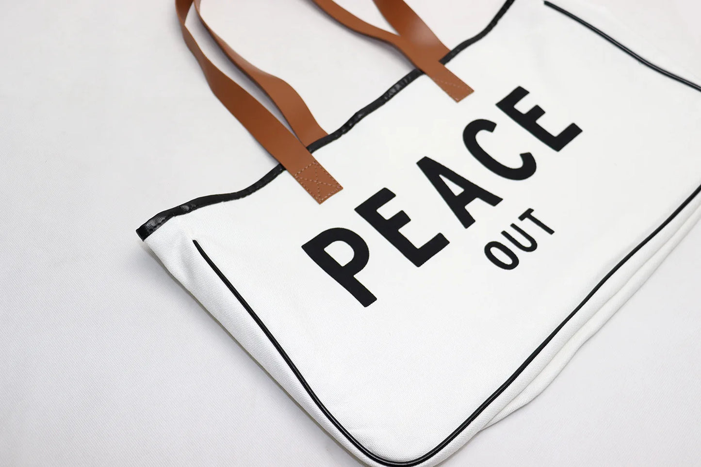 Tote bag with 'PEACE OUT' text on a white background