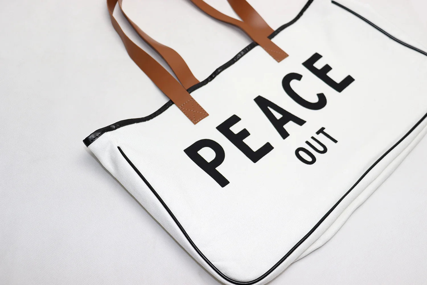 Tote bag with 'PEACE OUT' text on a white background