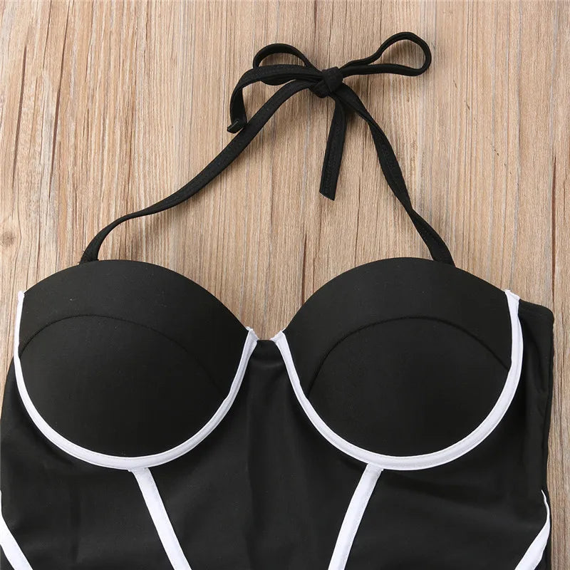 Black bikini top with white trim on a wooden surface