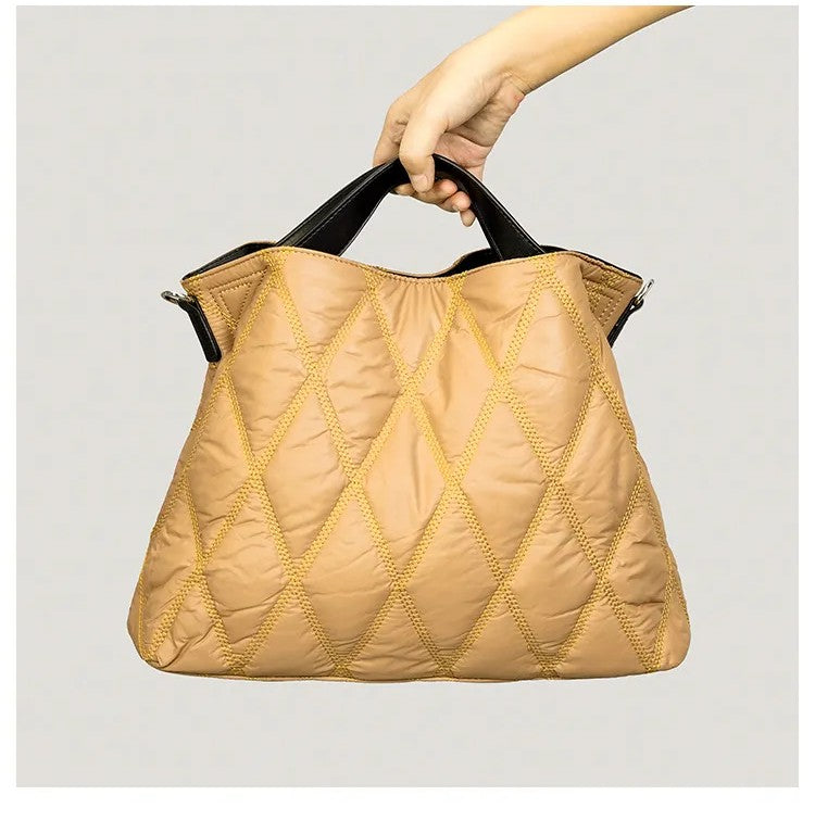 Beige quilted handbag held by a hand on a light gray background