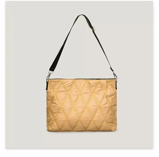 Beige quilted handbag with a black strap on a light gray background