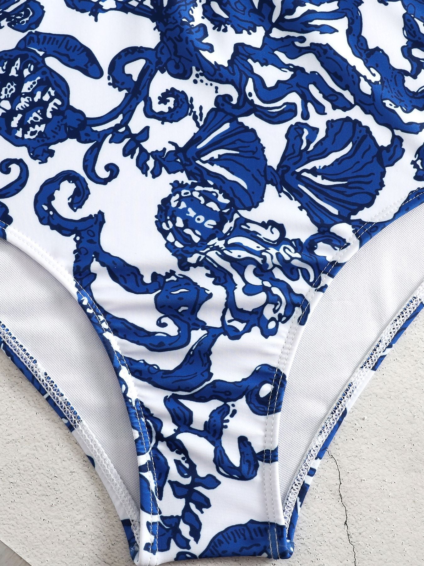 Blue and white patterned bikini bottom on a textured surface