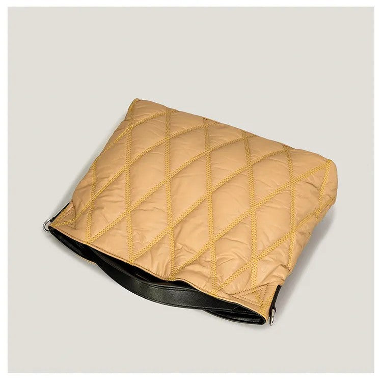 Beige quilted bag with black base on a light gray background