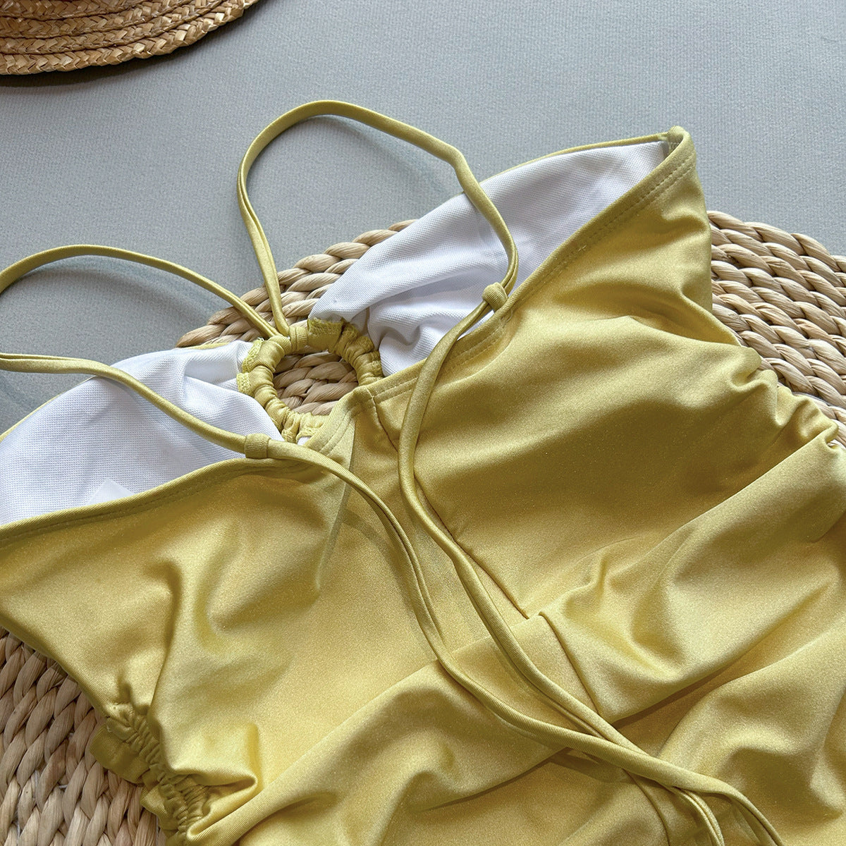 Yellow bikini top with white lining on a textured surface