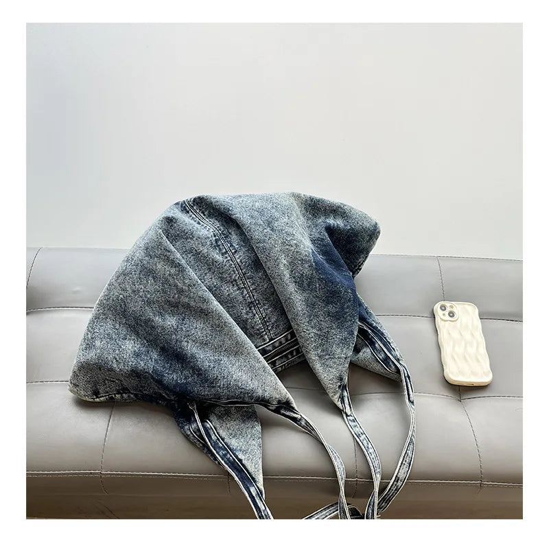 Denim tote bag draped over a chair with a phone on a gray surface