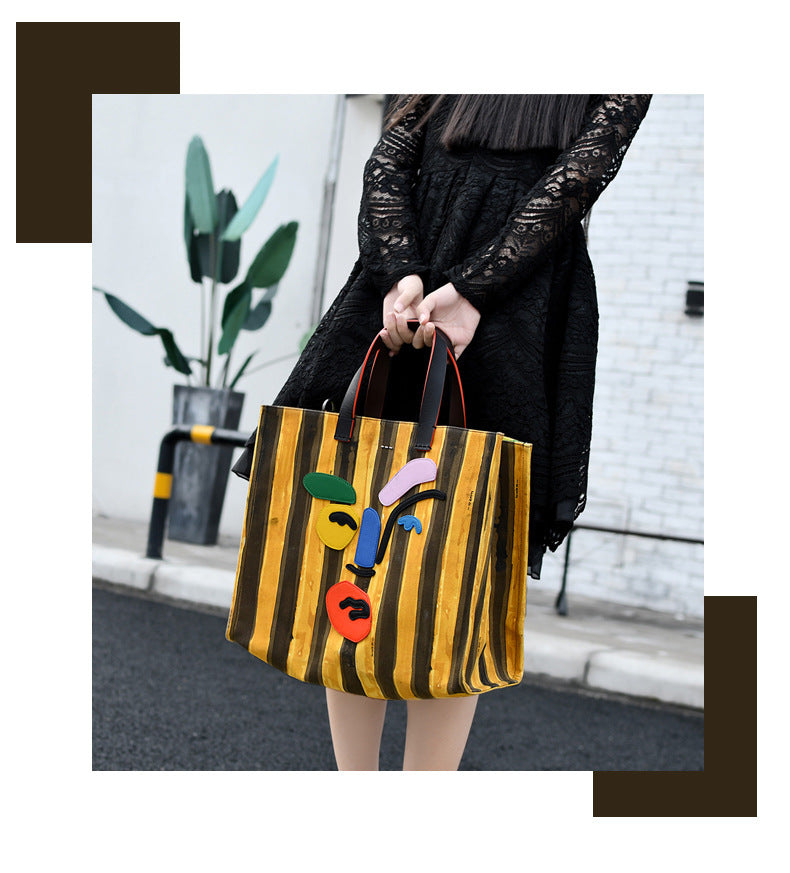 Person holding a colorful tote bag with abstract design on a street.