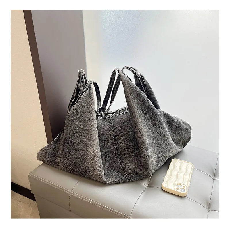 Gray denim handbag on a light gray surface with a blurred background