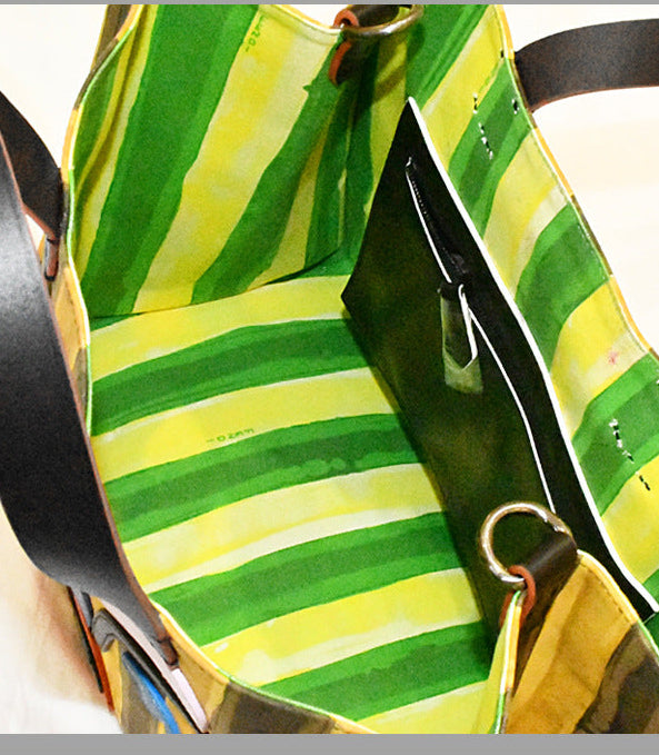 Green and yellow striped bag with black strap on a white background