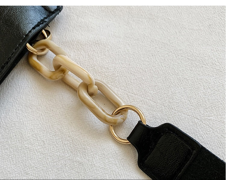 Close-up of a chain strap on a black bag with a white background