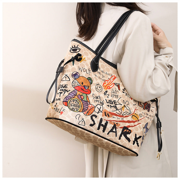 Handbag with colorful designs and text held by a person against a plain background